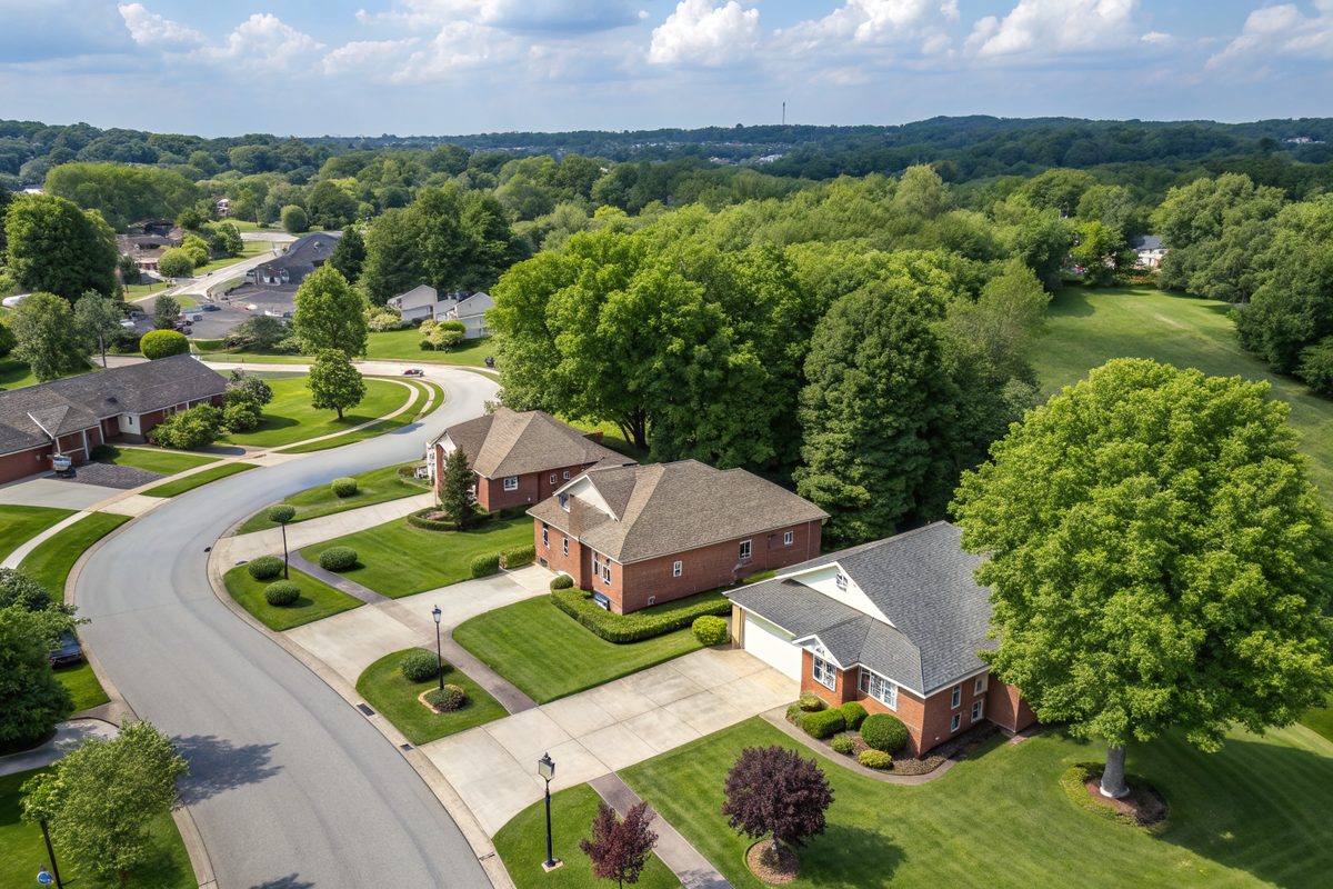 Aerial view of a leafy suburb of brick ranch and two-story homes along curving streets